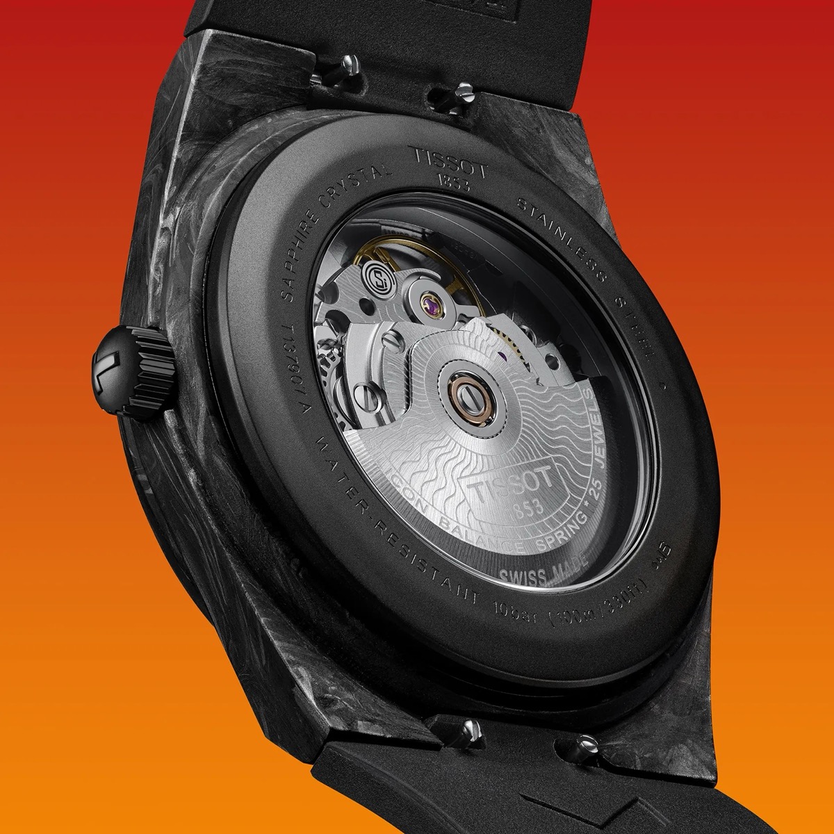 Vue rapprochée du fond de la montre Tissot PRX Powermatic 80 Carbone, montrant le mouvement automatique à travers le verre saphir et le boîtier noir en composite de carbone sur fond dégradé orange.