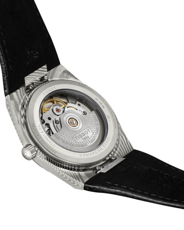 Vue arrière de la montre Tissot PRX Powermatic 80 Acier Damas, montrant le mouvement automatique à travers le fond transparent et le motif marbré de l’acier damas.