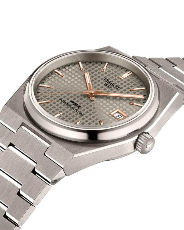 Gros plan sur la montre Tissot PRX Powermatic 80 Titane, avec cadran gris texturé, index et aiguilles dorés, et date à trois heures.