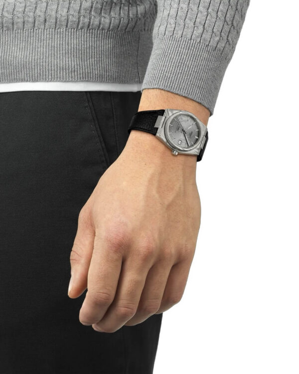 Montre Tissot PRX Powermatic 80 Acier Damas portée au poignet, avec boîtier marbré en acier damas et bracelet en cuir noir.