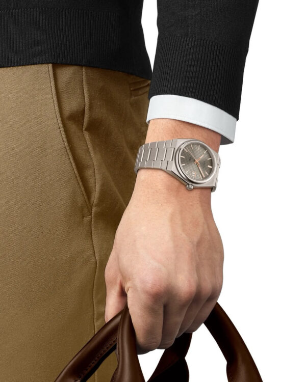 Montre Tissot PRX Powermatic 80 Titane portée au poignet, bracelet intégré en titane et cadran gris.